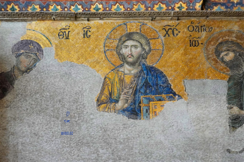 Fragment mozaiki Chrystusa Pantokratora z Hagia Sophia w Stambule, przedstawiający Jezusa z Maryją i Janem Chrzcicielem, na tle złotego tła, częściowo zniszczony przez upływ czasu.