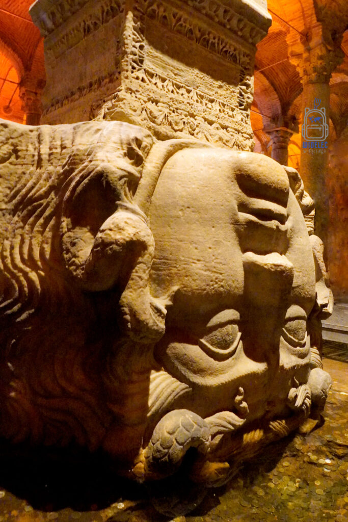 Głowa Meduzy, odwrócona do góry nogami, służąca jako baza kolumny w podziemnych Cysternach Justyniana w Stambule, otoczona misternymi rzeźbieniami i tajemniczym półmrokiem