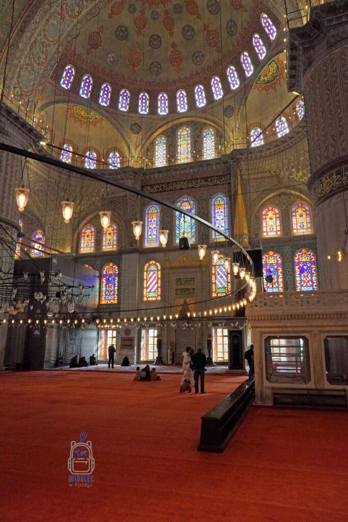 Wnętrze Błękitnego Meczetu w Stambule, ozdobione kolorowymi witrażami, bogatymi zdobieniami i misternie malowanymi kopułami. Jedno z najważniejszych miejsc historycznych w dzielnicy Sultanahmet, symbol architektury osmańskiej.