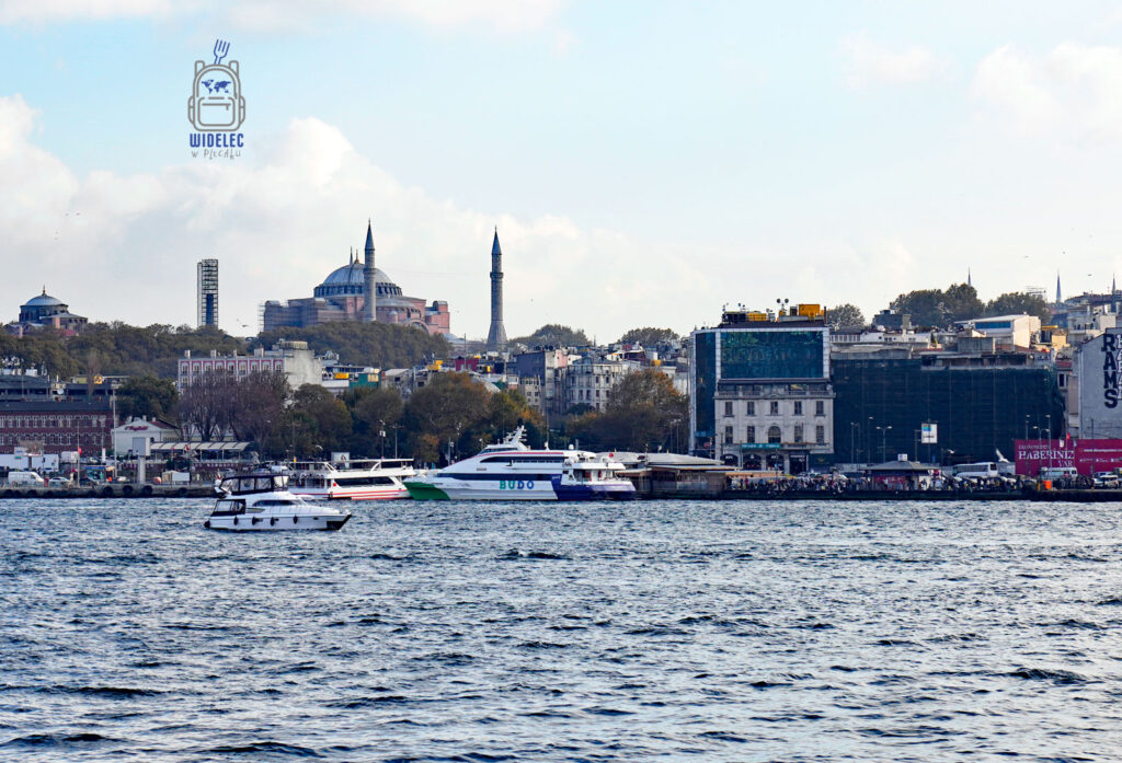 Widok na Sultanahmet w Stambule – Hagia Sophia i Błękitny Meczet widziane znad wód Bosforu, z przepływającymi promami i miejskim pejzażem w tle