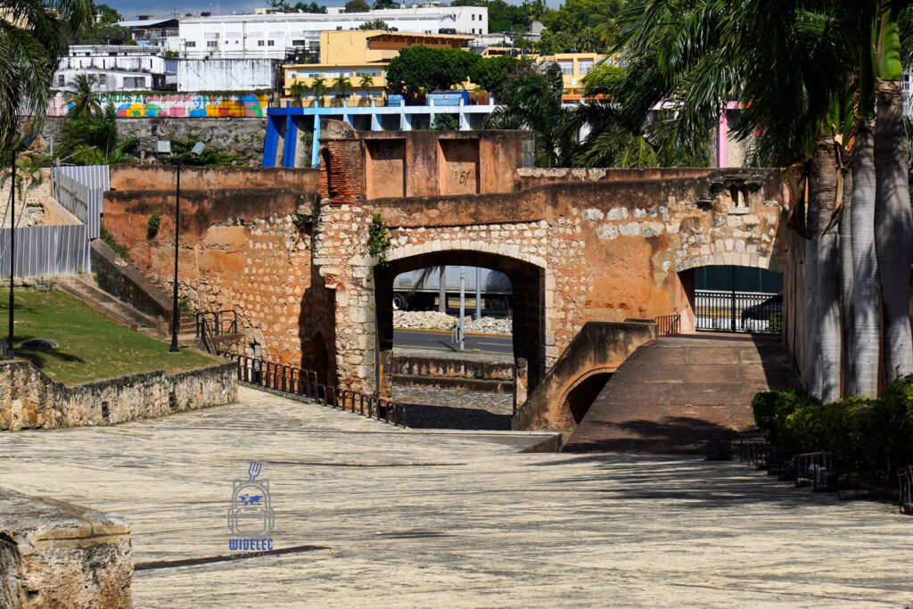Zdjęcie przedstawia Brama San Diego w Santo Domingo, zabytkowa kamienna konstrukcja z łukiem, prowadząca do starego miasta. W tle widoczne są kolorowe budynki i tropikalna roślinność, co podkreśla kulturowy i historyczny charakter miejsca
Dominikana - z wschodu na zachód - z południa na północ