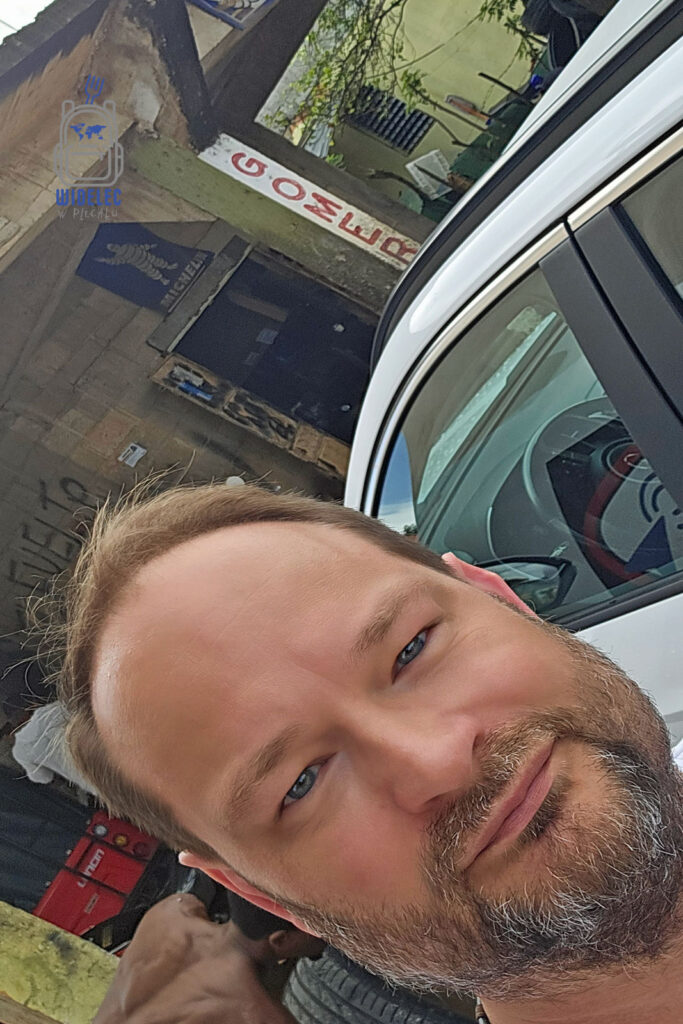 Selfie podróżnika przed warsztatem w Ameryce Łacińskiej – „Gomeria” to lokalny serwis opon. Widoczny biały samochód i skromny budynek warsztatu z ręcznie malowanym szyldem. Egzotyczna sceneria i autentyczna przygoda w podróży. #WidelecwPlecaku
Dominikana – Z wschodu na zachód - z południa na północ


