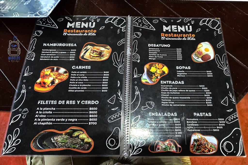 Menu restauracji na Dominikanie prezentujące różnorodne dania lokalnej kuchni. Zdjęcie ukazuje szeroką gamę posiłków dostępnych dla turystów, w tym śniadania z kawą i jajkami, różnorodne dania główne z kurczaka, wieprzowiny i owoców morza, oraz desery jak flambirowany banan. Ceny są wyrażone w dominikańskich pesos, co pozwala na lepsze zrozumienie kosztów życia na wyspie. W menu widoczne są także ceny popularnych napojów, takich jak woda, soki, piwo i koktajle, oferując pełny przegląd możliwości gastronomicznych dla odwiedzających. Zdjęcie ilustruje autentyczne doświadczenie kulinarnie na Dominikanie, idealne dla podróżników szukających lokalnych smaków poza turystycznymi kurortami