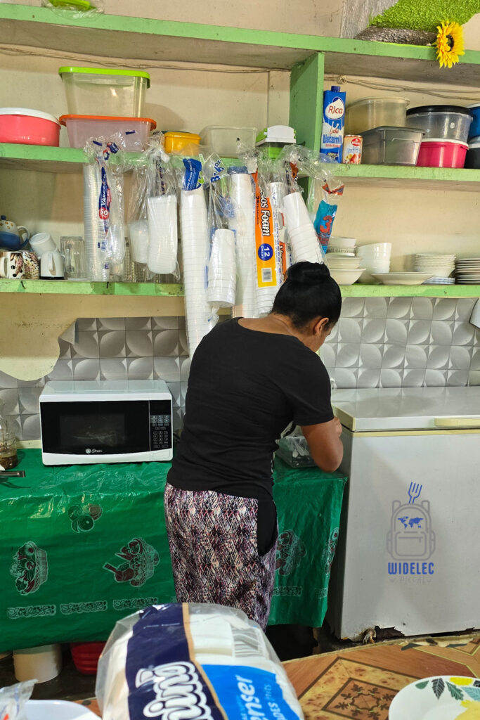 Kobieta przygotowuje jedzenie w kuchni lokalnej restauracji na Dominikanie. Scena odbywa się w niewielkim, ale zorganizowanym pomieszczeniu z zielonymi ścianami, gdzie na półkach widoczne są różnorodne kuchenne akcesoria i opakowania. Pracowita atmosfera tej kuchni podkreśla autentyczność i domowy charakter miejsc, gdzie przygotowywane są tradycyjne dominikańskie posiłki
#widelecwpleacaku
#dominikana - z wschodu na zachód - z południa na północ