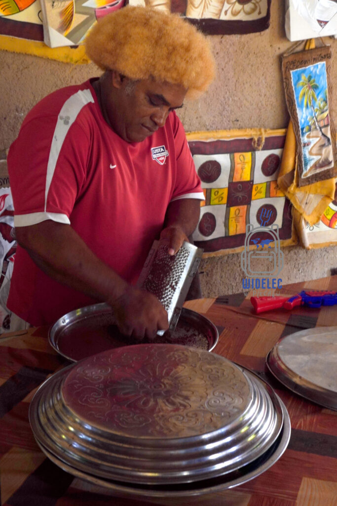 Utalentowany kucharz z Dominikany, ubrany w czerwoną koszulkę z logiem USA, przygotowuje lokalny deser. Mężczyzna skupiony na swojej pracy, trze kakao do miski, co jest kluczowym składnikiem tradycyjnego deseru z dodatkiem miodu i rumu. Scena ta odbywa się w kuchni pełnej kolorowych elementów dekoracyjnych, co dodaje uroku lokalnym przysmakom
#widelecwpleacaku
#dominikana - z wschodu na zachód - z południa na północ
