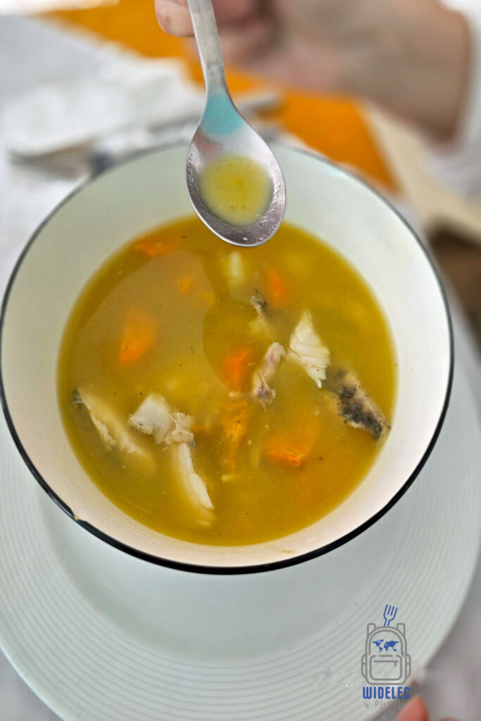 Tradycyjna dominikańska zupa rybna podana na białym talerzu. Widać kawałki ryby i warzyw pływające w złocistym, klarownym bulionie. Na pierwszym planie zdjęcia znajduje się łyżka unosząca kroplę bulionu, co podkreśla świeżość i smak potrawy. Zdjęcie oddaje kulinarną tradycję Dominikany, gdzie proste składniki zamieniają się w smaczne dania
#widelecwpleacaku
#dominikana - z wschodu na zachód - z południa na północ