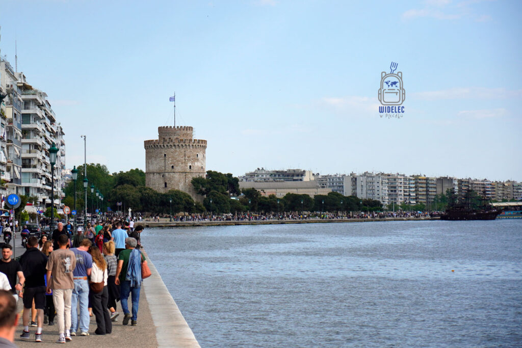 Widok na Białą Wieżę i nadmorską promenadę w Salonikach, tłumy spacerowiczów nad Morzem Egejskim
