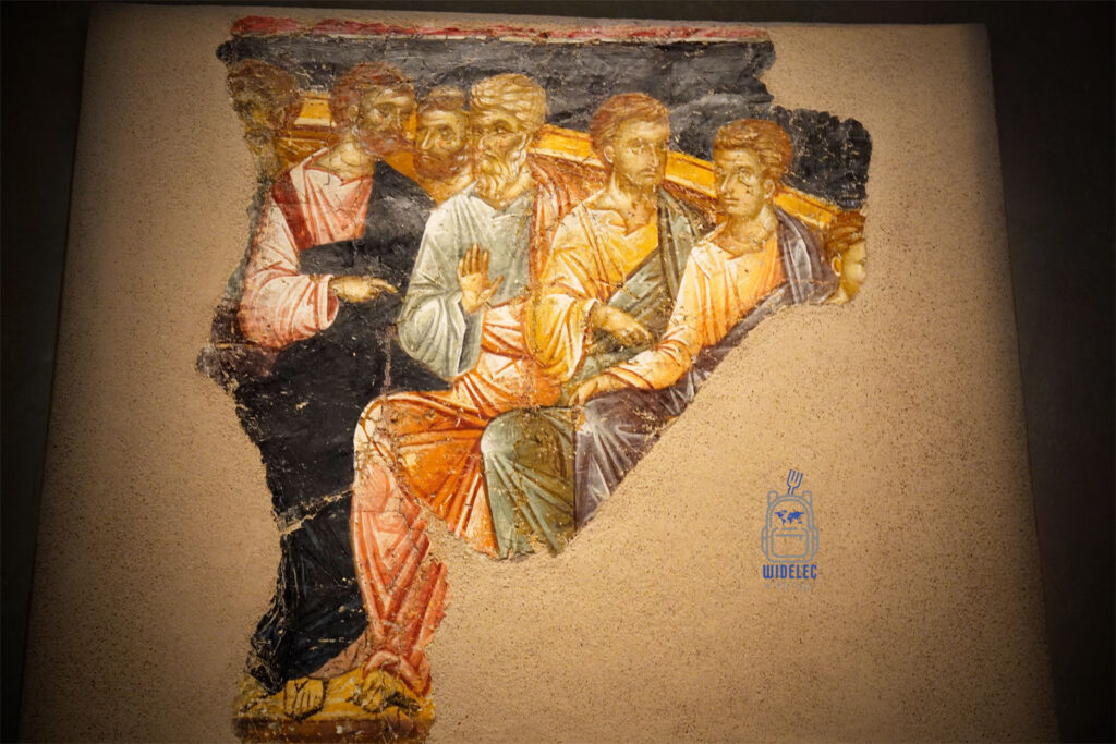 Zachowany fragment bizantyjskiego fresku przedstawiający apostołów w rozmowie, ekspresyjna scena malowana na tynku