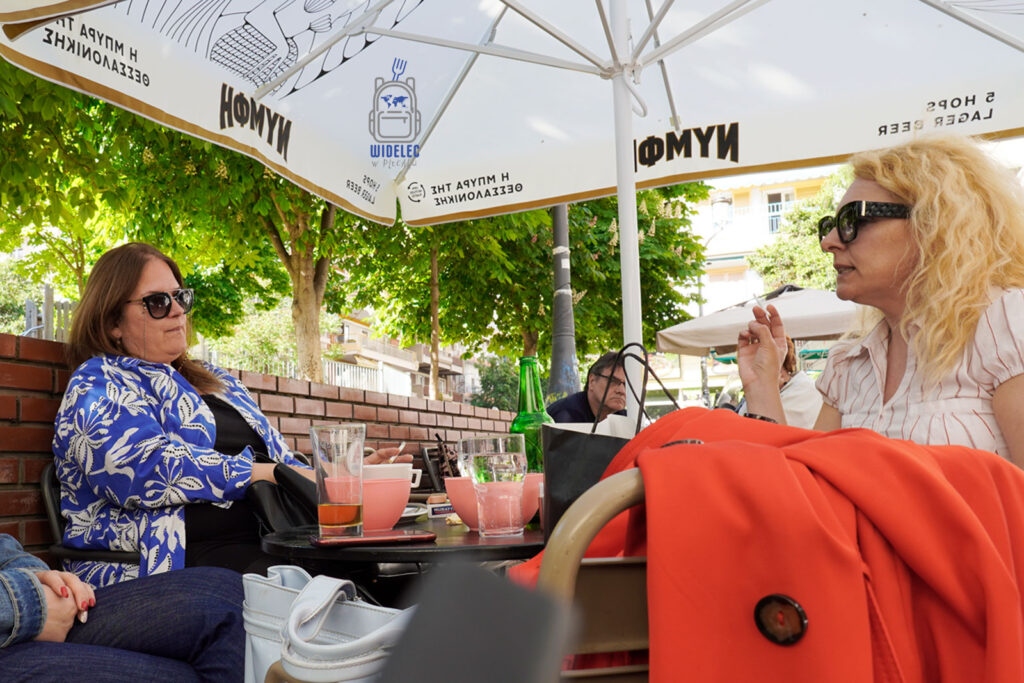 Greczynki w kawiarni w Salonikach podczas rozmowy przy kawie – grecki slow life, codzienność i kultura towarzyska w cieniu drzew. Saloniki – Bogowie, Galeriusz i Gyros, widelecwplecaku.pl.