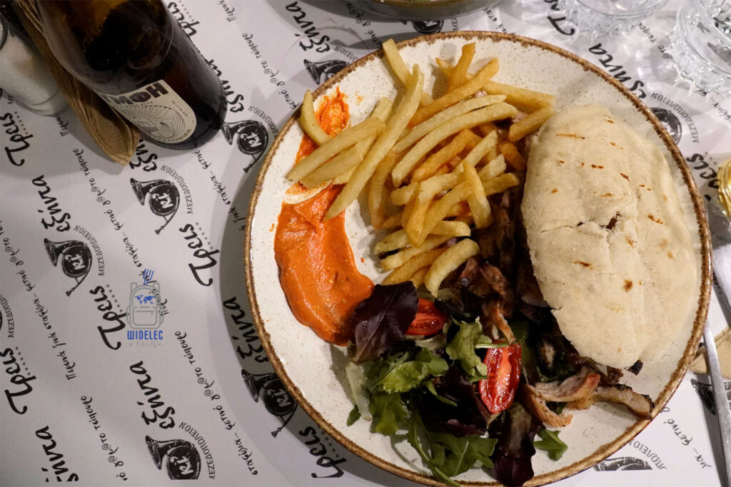 Tradycyjny gyros po salonicku – serwowany z frytkami, świeżą pitą, sałatką i kremowym sosem paprykowym w greckiej tawernie.