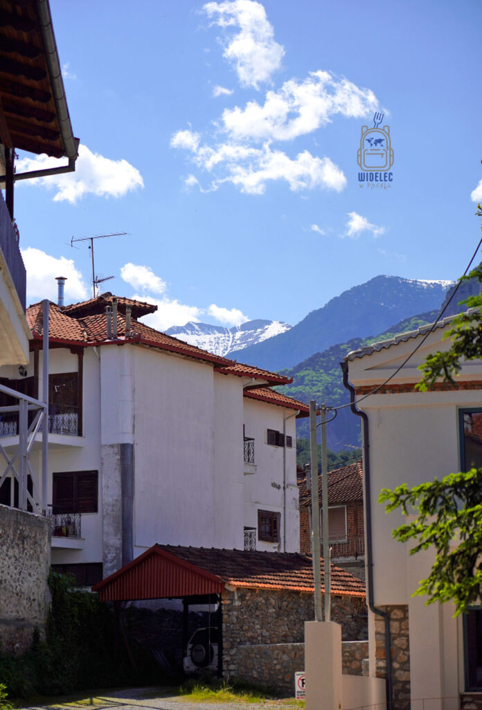 Uliczka w Litochoro z widokiem na ośnieżone szczyty Olimpu – codzienne życie u podnóża świętej góry Grecji. Saloniki – Bogowie, Galeriusz i Gyros, widelecwplecaku.pl.
