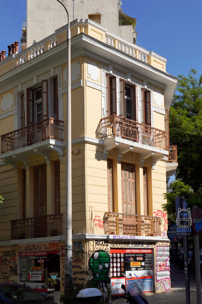 Neoklasycystyczna kamienica w Salonikach z eleganckimi balkonami i zdobieniami, której parter został zdominowany przez graffiti i reklamy – symbol kontrastów miasta.