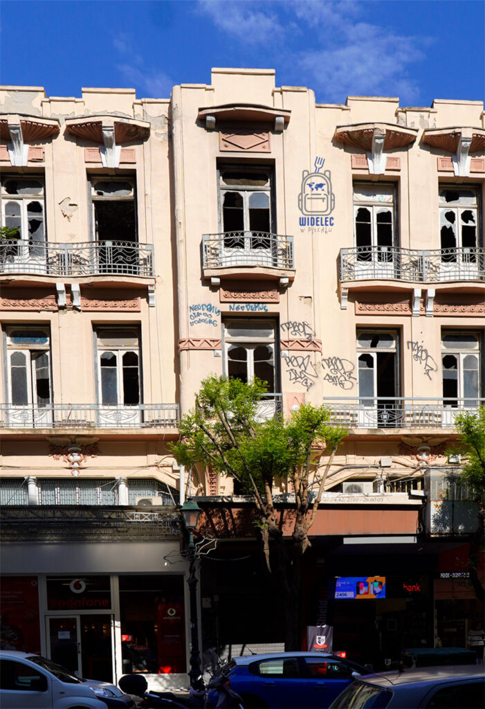 Zniszczona neoklasycystyczna kamienica przy ulicy Egnatia w Salonikach – wybite szyby, graffiti i ślady dawnej elegancji nad tętniącą życiem ulicą.
