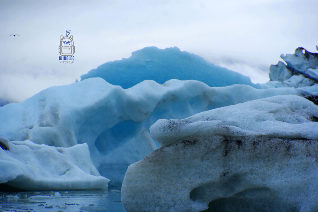 Błękitne bryły lodu unoszące się na wodzie u podnóża lodowca Vatnajökull w Islandii, widelecwplecaku.pl