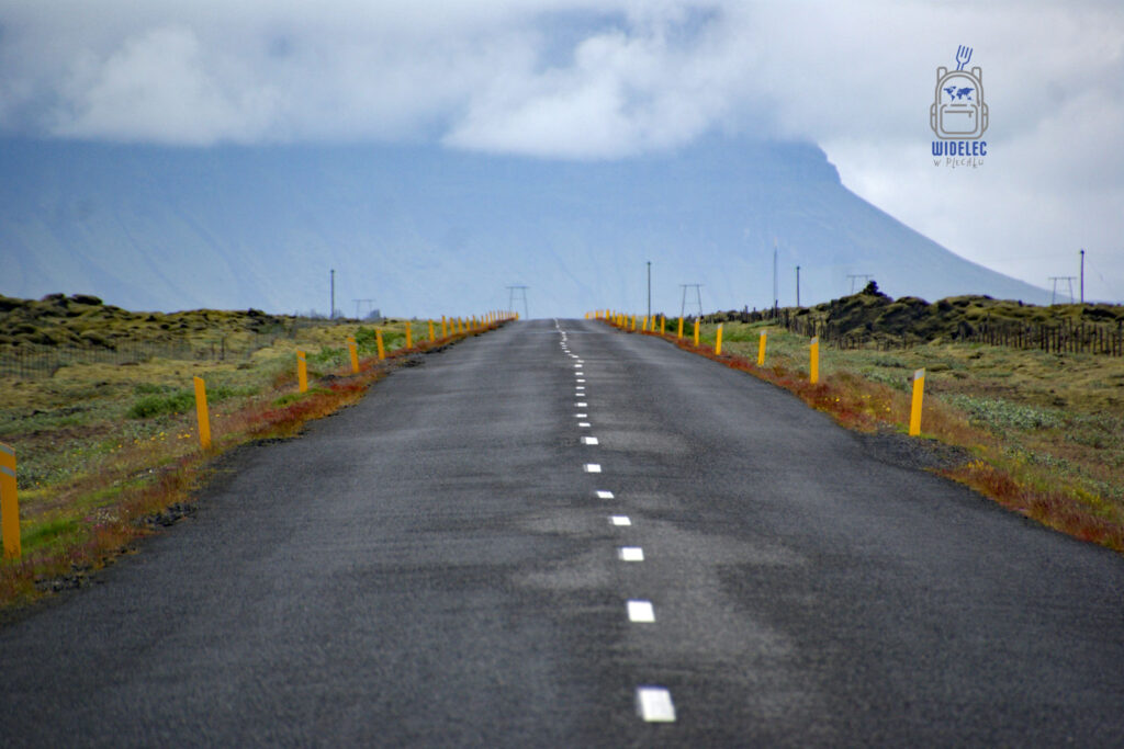 Ring Road nr 1, pusta asfaltowa droga przez pola lawy; żółte słupki prowadzą ku zamglonym górom, surowy krajobraz – widelecwplecaku.pl