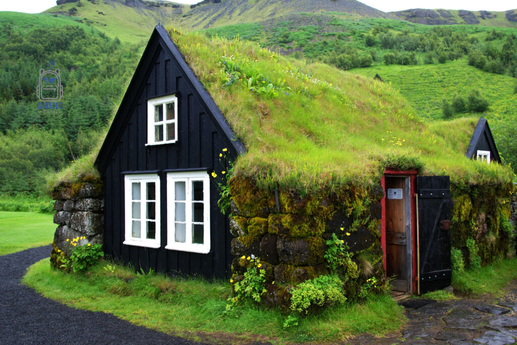 Islandia – tradycyjny dom torfowy w muzeum Skógasafn w Skógar, czarne ściany i dach porośnięty trawą wtapiają się w zielony krajobraz; dziedzictwo kulturowe wyspy – widelecwplecaku.pl