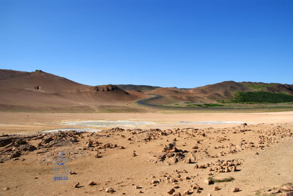 Pustynny krajobraz geotermalnego obszaru Námafjall Hverir z wijącą się drogą i górami w tle, widelecwplecaku.pl
