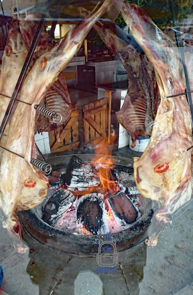 Tradycyjne argentyńskie asado przygotowywane nad ogniem – duże kawałki mięsa pieczone przy żarze podczas kulinarnej podróży po Argentynie. Kuchnia argentyńska, steki i Patagonia – widelecwplecaku.pl