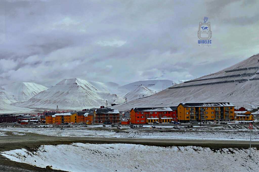 Panorama Longyearbyen z kolorowymi budynkami otoczonymi górami i dawnymi konstrukcjami kolejki węglowej.