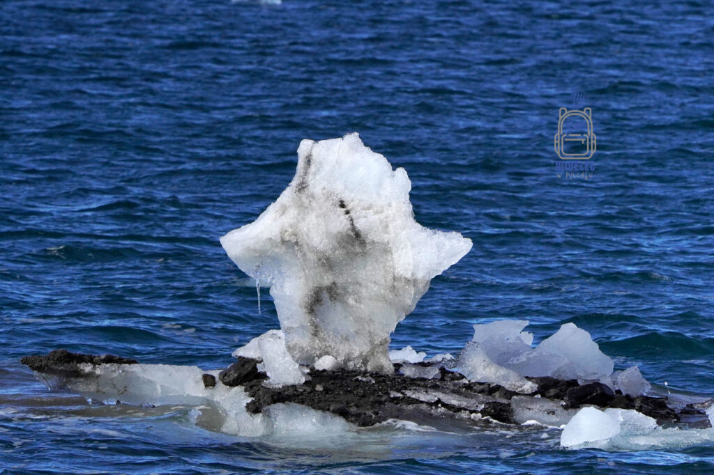 pojedyncza kra w kształcie człowieka dryfująca po ciemnoniebieskim morzu. Svalbard, Arktyka