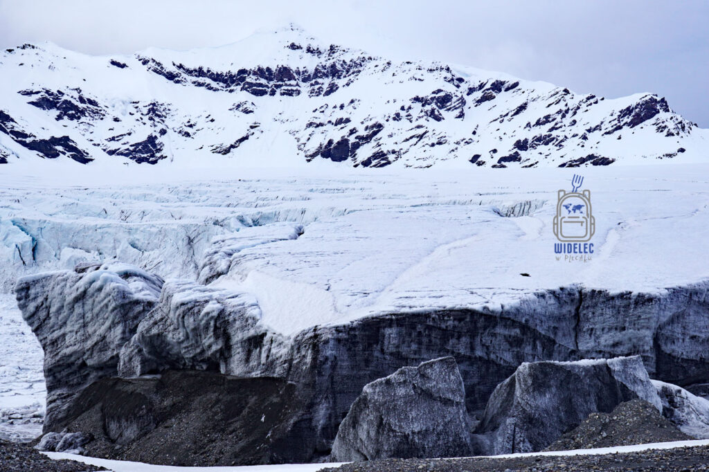 lodowiec pokrywający skały i małą grotę. Svalbard, Arktyka