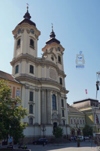 Barokowy kościół św. Antoniego z Padwy, zwany kościołem Minorytów, przy placu Istvána Dobó w Egerze na Węgrzech. Monumentalna fasada z dwiema wieżami zegarowymi, ozdobnymi kolumnami i rzeźbami na tle błękitnego nieba